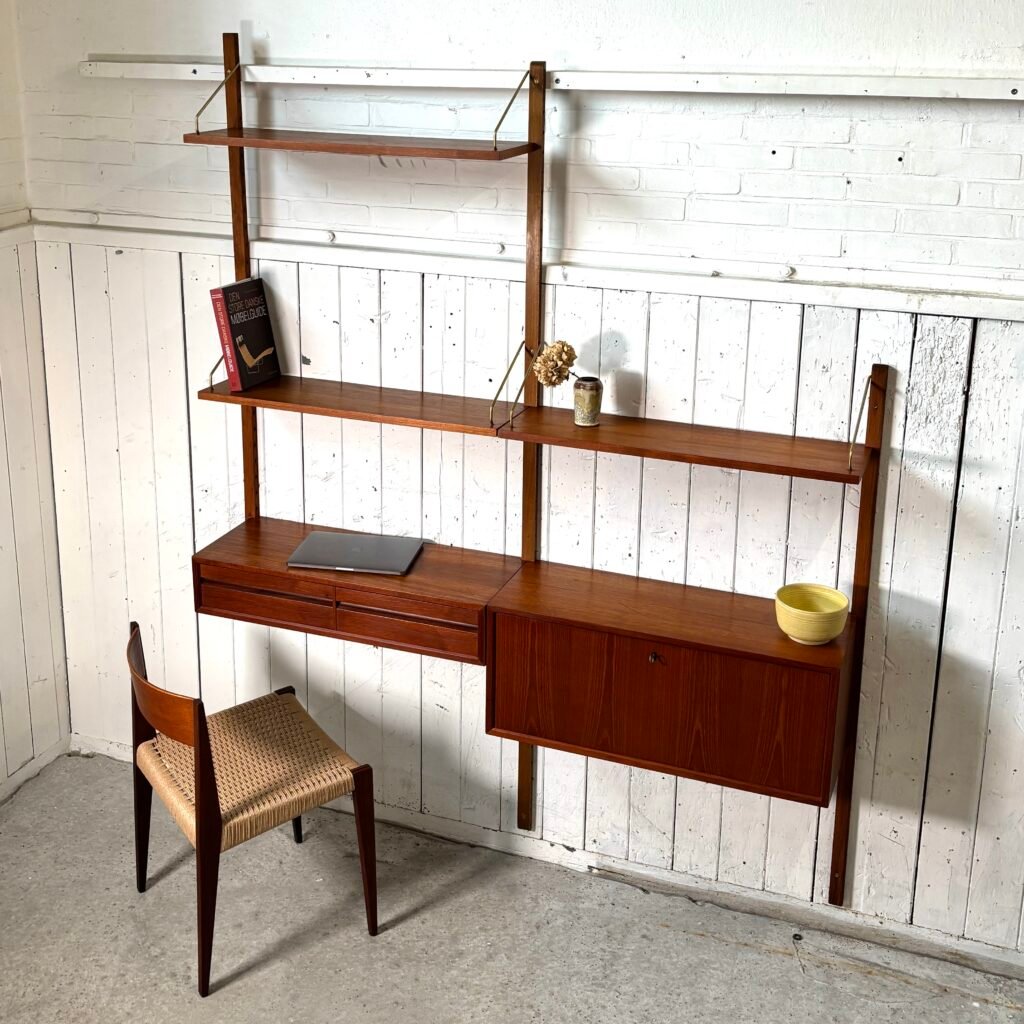 Mid-century modern teak wall-mounted shelving unit with built-in desk and chair against a white wooden wall.
